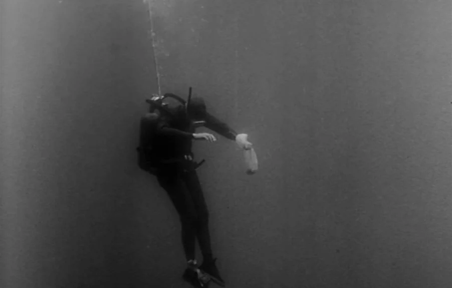 Caltiki, The Immortal Monster (1959) movie still: fullbody — A diver floats suspended in deep, dark open water with minimal visibility. The diver…