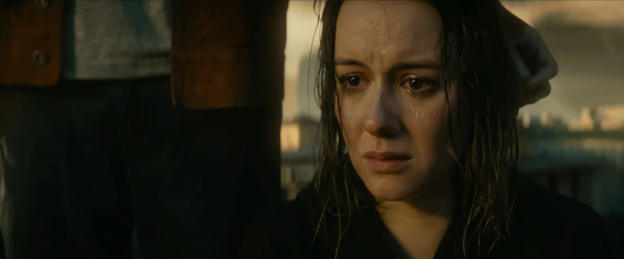 Invasion (2020) movie still: closeup — An outdoor rooftop setting at dusk features a cityscape blurred in the distance. A woman with wet hair has a…