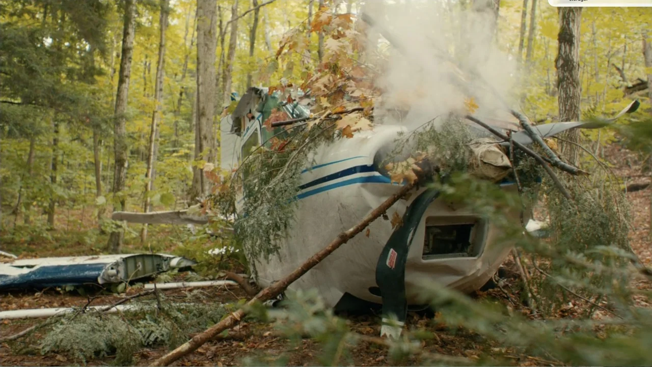 National Parks Adventure (2016) movie still: medium — A damaged small white airplane lies resting on the forest floor surrounded by trees. Thick…