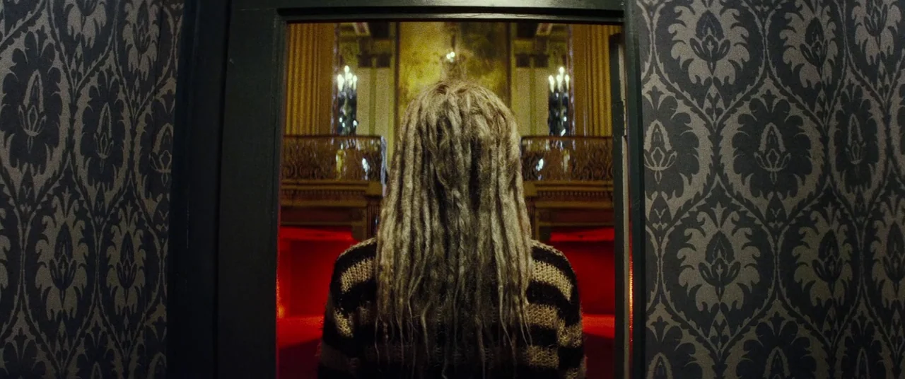 Lords Of Salem (2013) movie still: medium — A dark frame is flanked by ornate black and grey patterned wallpaper. A person stands in the center…
