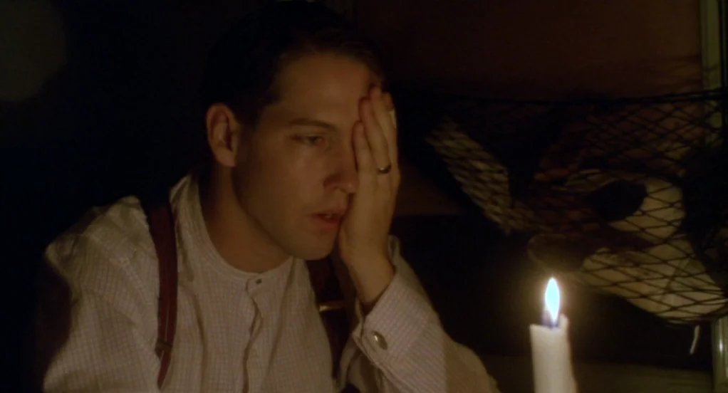 Eight Men Out (1988) movie still: medium — A man sits in a darkened space lit only by a single candle. He rests his hand over his eye while wearing…