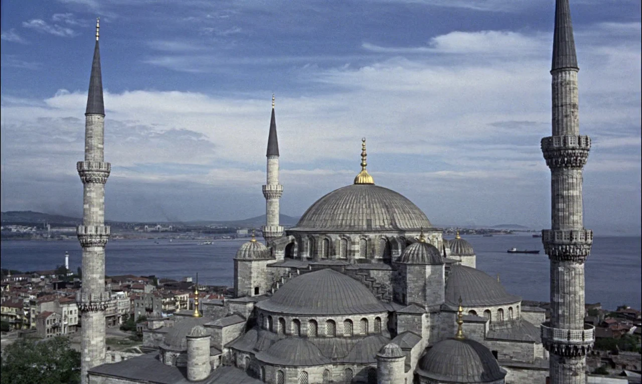 From Russia With Love (1963) movie still: establishing — An ancient stone mosque with multiple domes and tall minarets overlooks a wide bay. The…