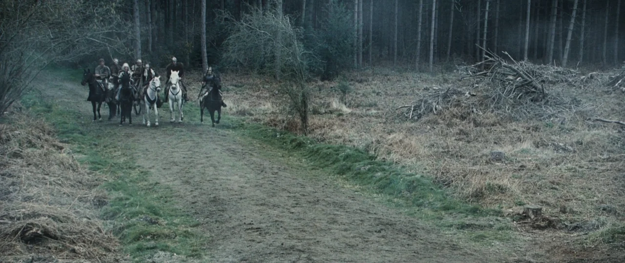 Centurion (2010) movie still: wide — A group of armored horsemen travel along a dirt trail through dense pine woods. They are positioned in the…