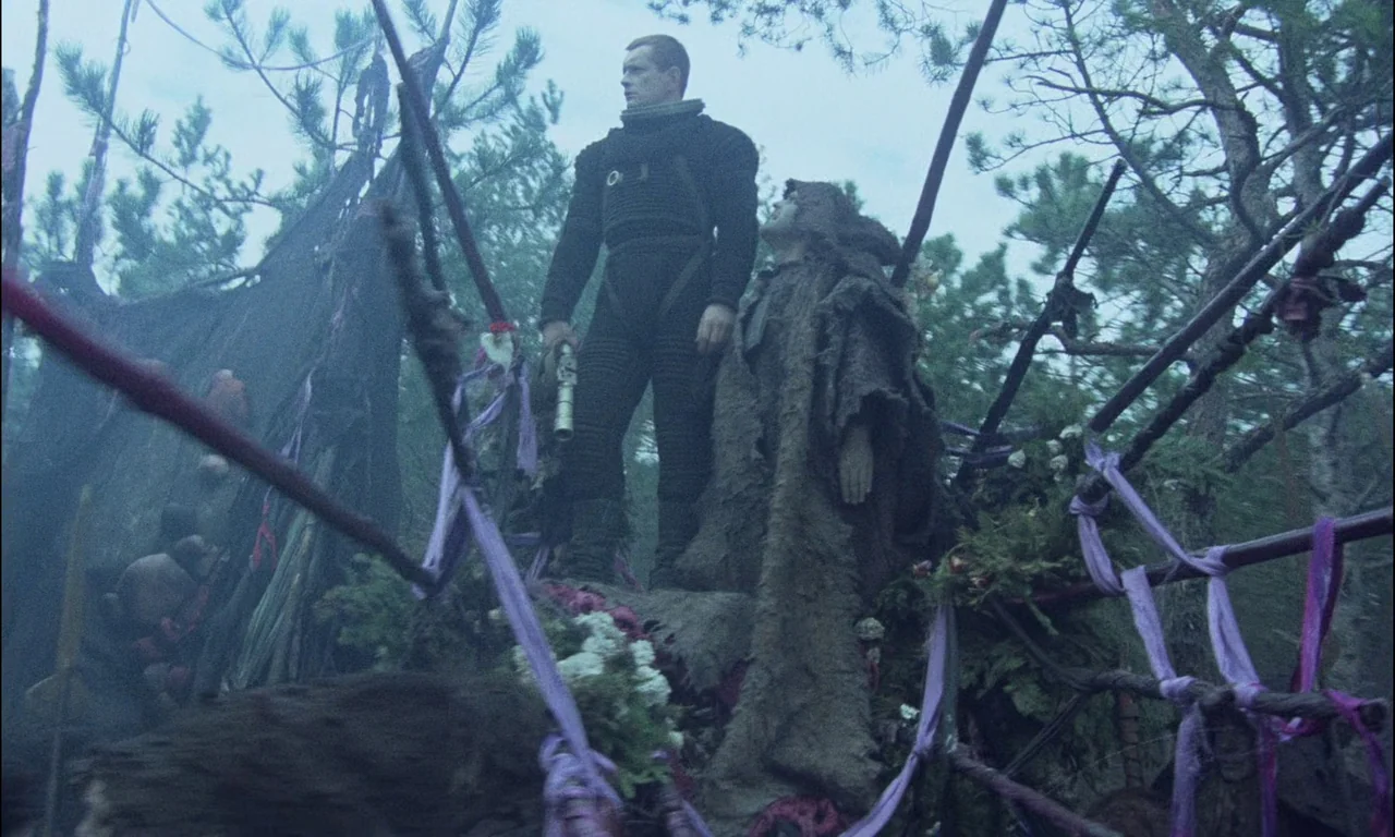 On The Silver Globe (1988) movie still: fullbody — A woodland ritual site features elaborate wooden structures decorated with purple fabric and…