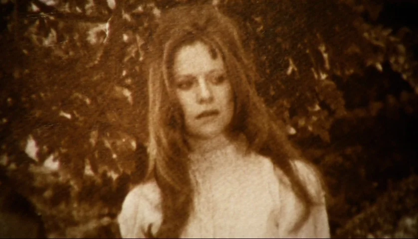 Let’s Scare Jessica To Death (1971) movie still: closeup — An outdoor setting features a woman posed against a blurred backdrop of dark foliage. The…