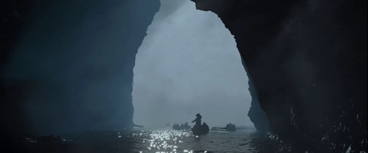 Pirates of the Caribbean: The Curse of the Black Pearl movie still: wide — A dark, cavernous opening framed by jagged rock faces reveals a bright,…