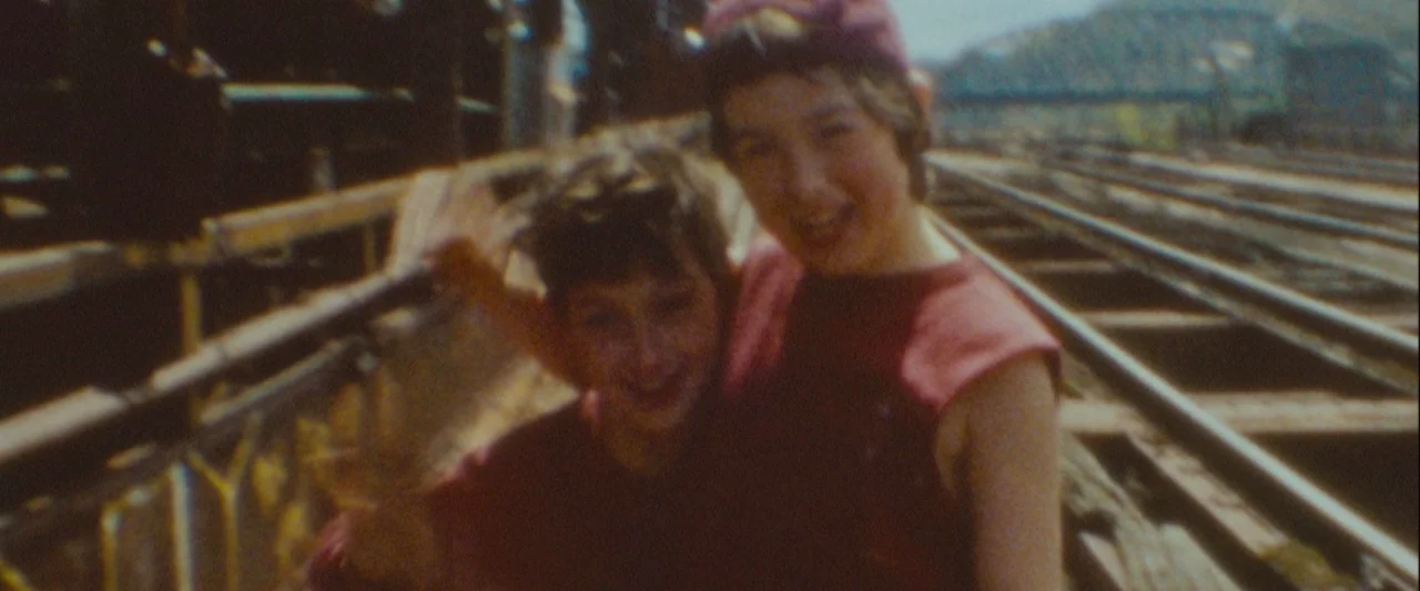 Out of the Furnace (2013) movie still: medium — Two children stand together on elevated railway tracks with an industrial steel bridge visible…