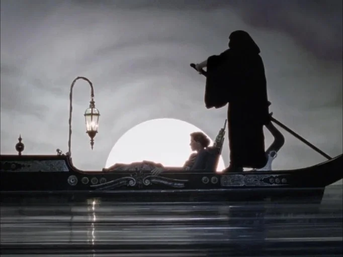 The Souvenir: Part II (2021) movie still: wide — A decorative boat moves across a body of water under a large bright moon. A hooded figure stands at…