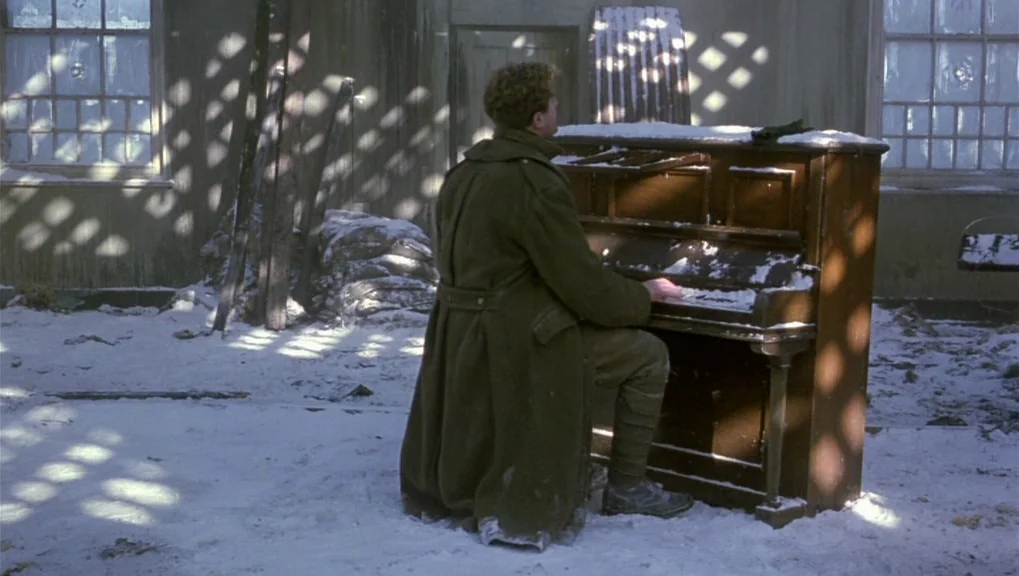 War Requiem (1989) movie still: fullbody — An open-roof structure with snow-covered floors and walls in a state of decay. A man wearing a military…