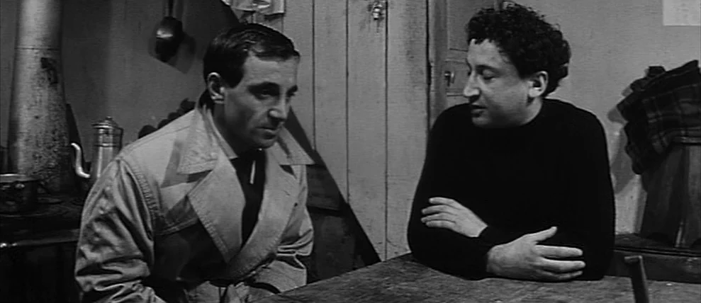 Shoot The Piano Player (Tirez Sur Le Pianiste) (1960) movie still: medium — A spartan room features wooden walls, a metal stove, and a rustic table.…