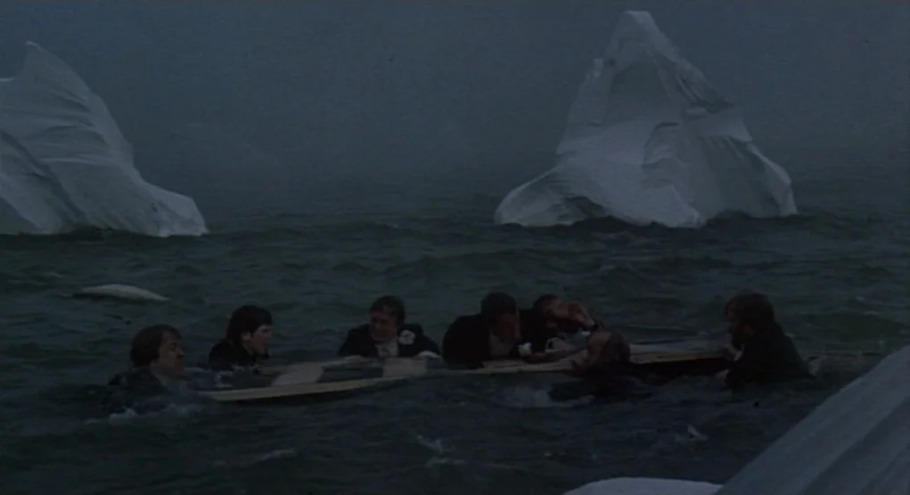 Time Bandits (1981) movie still: wide — A group of men in suits cling to a wooden board in dark water. Large icebergs rise from the freezing sea…