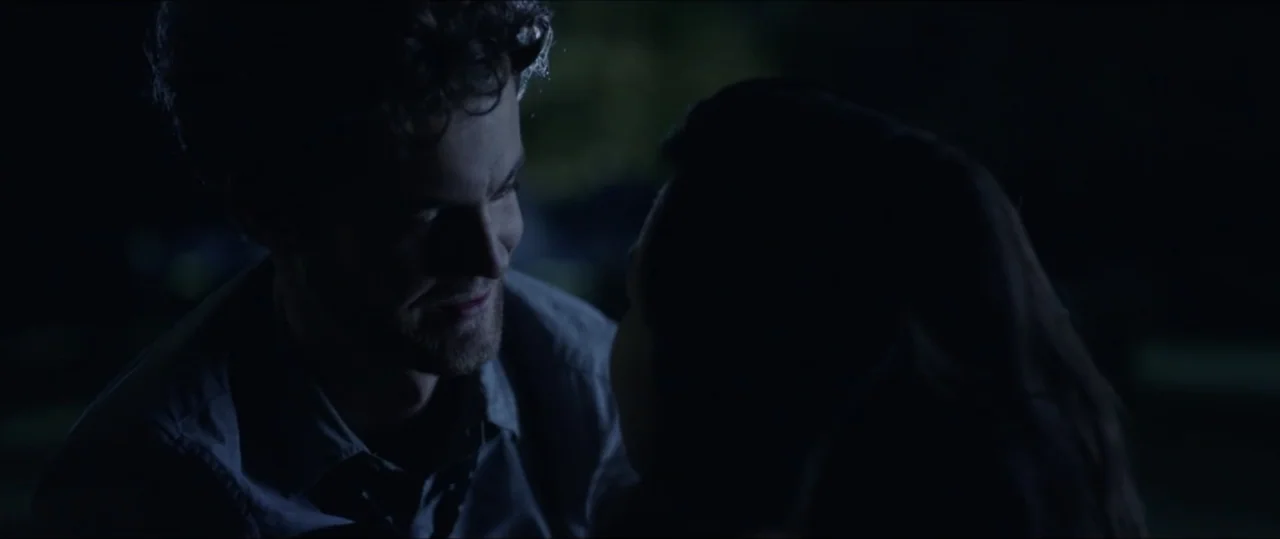 Plus One (2019) movie still: medium — A man and a woman stand face to face in a darkened outdoor environment at night. They appear to be in the…
