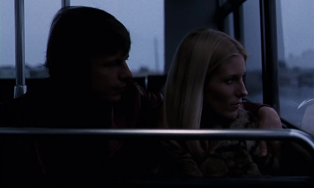 Daughters of Darkness (1971) movie still: medium — A dark, cramped interior of a bus at dusk with windows overlooking a blurred landscape. A man…