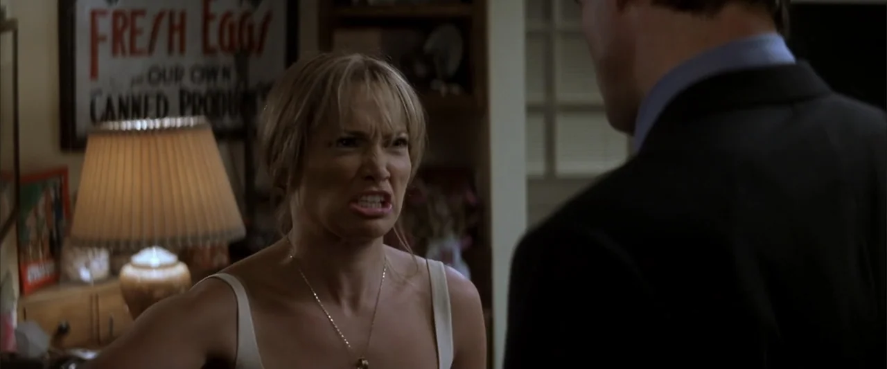 Enough (2002) movie still: medium — A dimly lit room with a 'Fresh Eggs' sign visible on the wall behind. A woman with a strained facial expression…