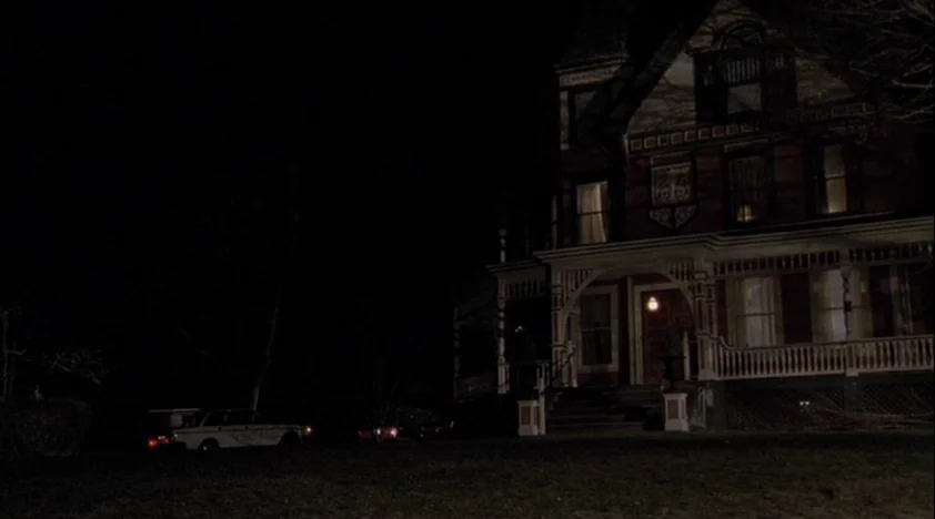 The House Of The Devil (2009) movie still: establishing — A large, multi-story Victorian mansion stands in darkness at night. The structure is…