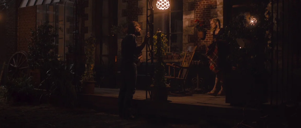 Broken Circle Breakdown (2012) movie still: wide — A night scene on the wooden porch of a red brick house with potted plants. A man and a woman…