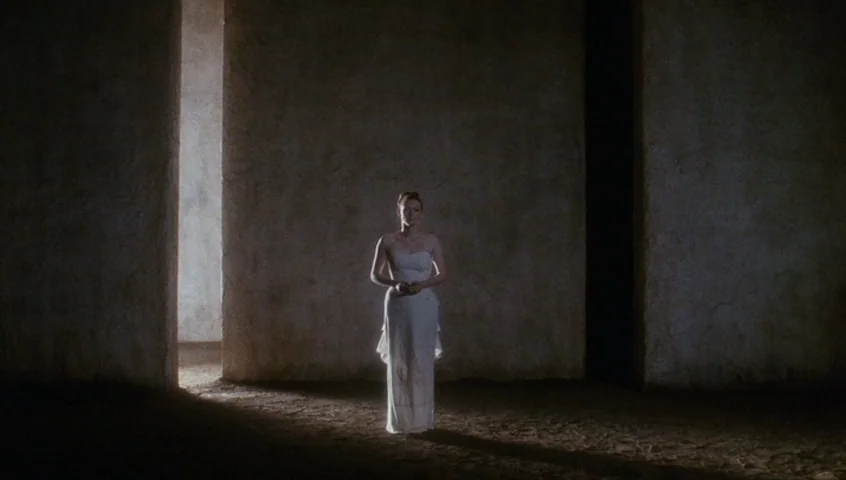 Edward II (1991) movie still: fullbody — A vast, minimalist interior features tall stone walls with vertical architectural slits for light. A lone…