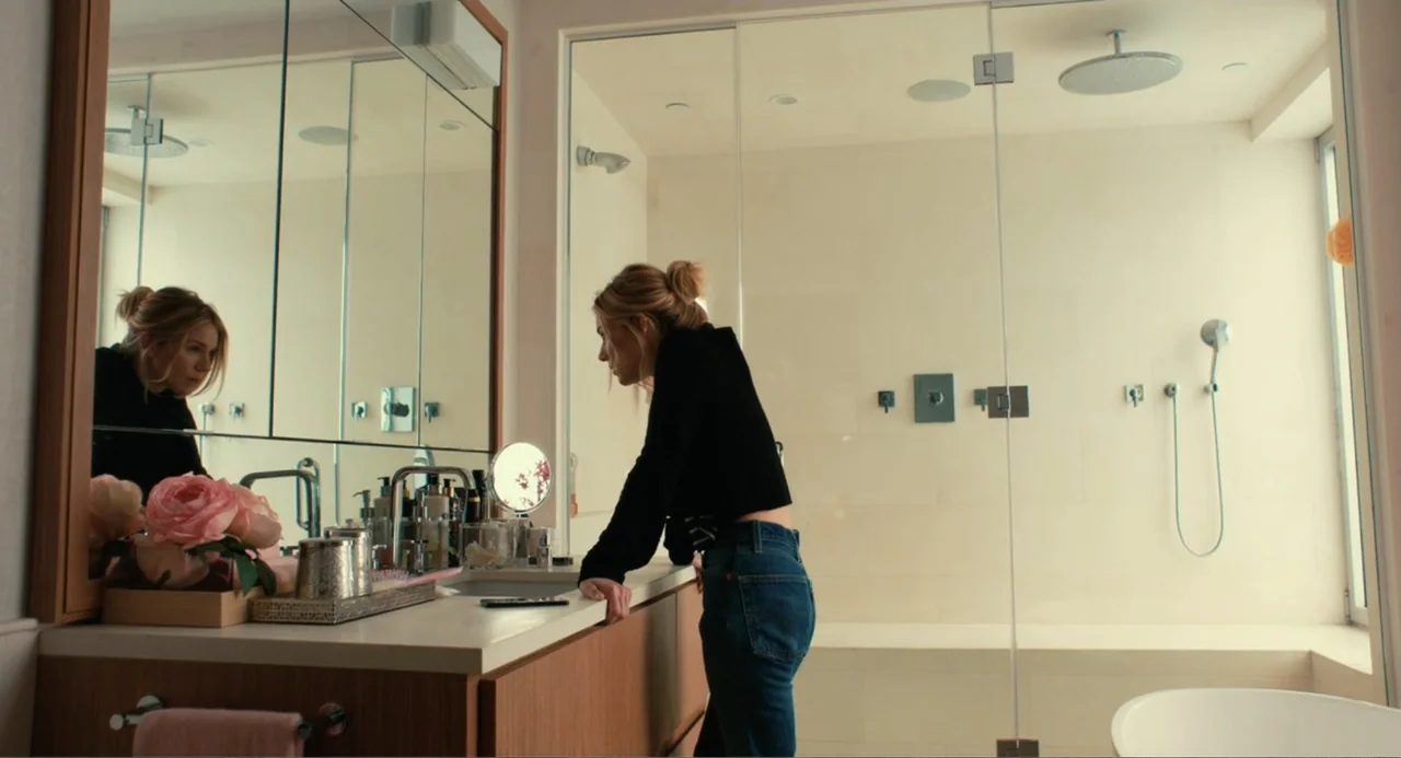 An Imperfect Murder (2017) movie still: medium — A modern, bright bathroom features a vanity with a large mirror and glass shower enclosure. A…