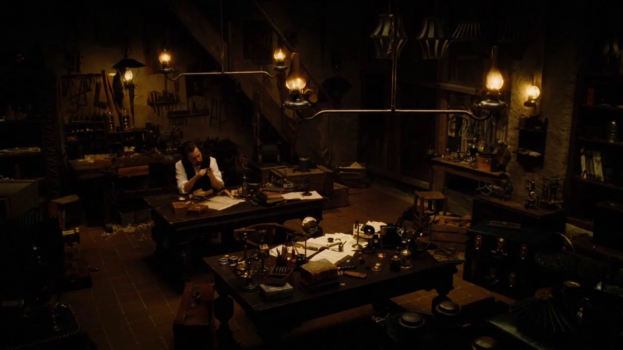 The Illusionist (2006) movie still: wide — A cluttered workshop filled with wooden tables, mechanical tools, and vintage optical instruments. A lone…