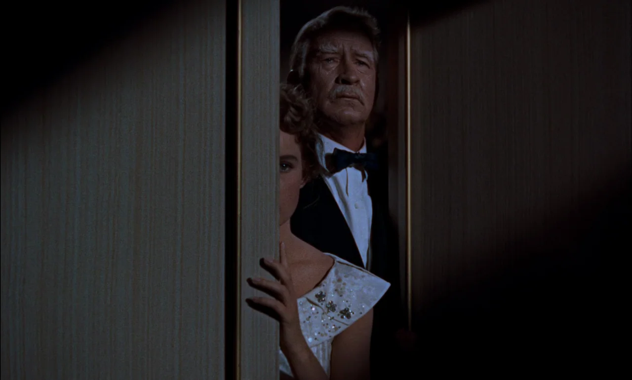Giant (1956) movie still: medium — An older man and a young woman stand behind a partially opened wooden door. They look through the narrow gap into…