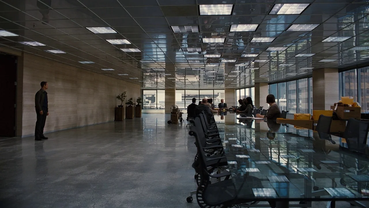 The Dark Knight Rises (2012) movie still: wide — A minimalist corporate conference room with reflective polished floors and a glass table. A group…