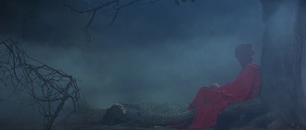 The Masque of the Red Death (1964) movie still: wide — A dark, misty woodland area features a single tree with gnarled bare branches. A lone figure…