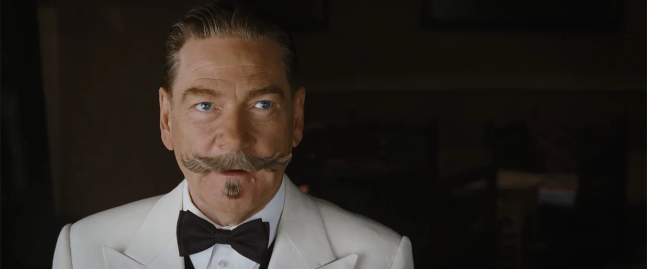 Death on the Nile (2022) movie still: closeup — An interior space with dark, blurred background elements suggesting a restaurant or dining area. A…