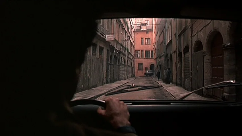 The Unbearable Lightness of Being (1988) movie still: medium — A narrow European urban alleyway features tall residential buildings with arched…