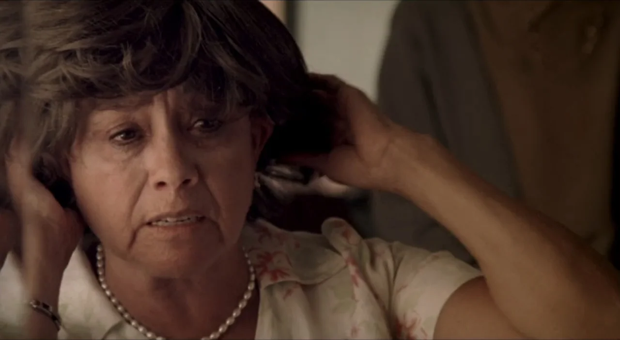 Sex, Love And Other Perversions II (2006) movie still: closeup — An interior space with a person in the foreground. A woman adjusts her hair while…