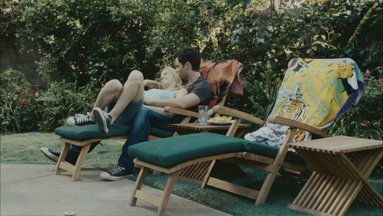The Stepfather (2009) movie still: medium — A residential patio featuring two wooden lounge chairs set amidst thick green bushes. A young man and…
