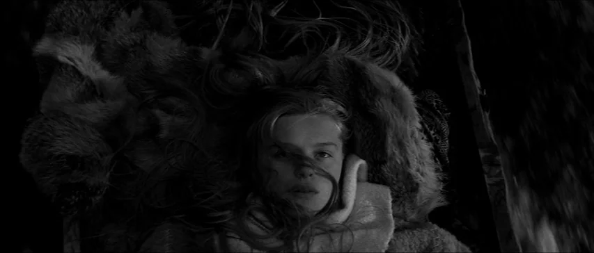 Marketa Lazarová (1967) movie still: closeup — A woman lies on a bed of thick fur inside a dark wooden vehicle. She stares directly upward toward…