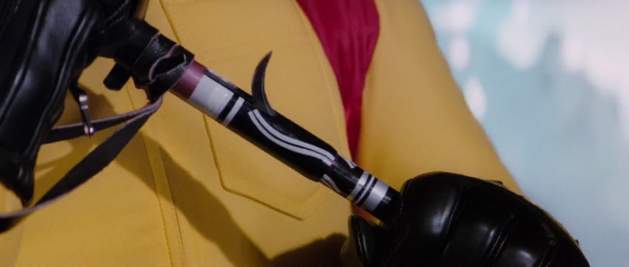 The Spy Who Loved Me (1977) movie still: closeup — Close-up view of a black tactical baton held by a person in yellow clothing. The baton features…