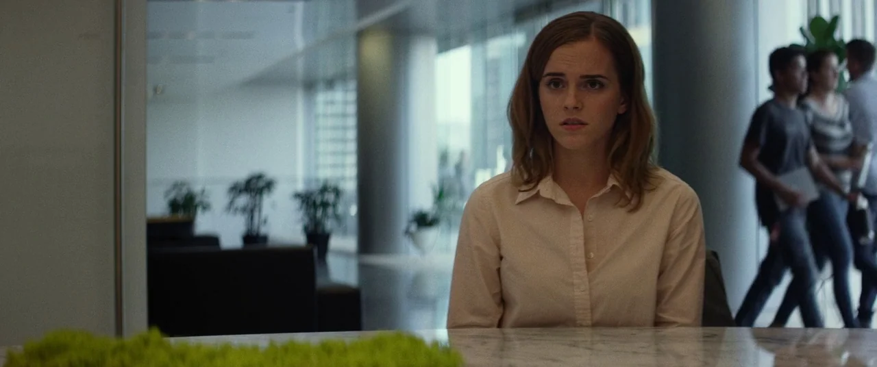 The Circle (2017) movie still: medium — A modern glass-walled corporate lobby features polished marble surfaces and potted greenery. A young woman…
