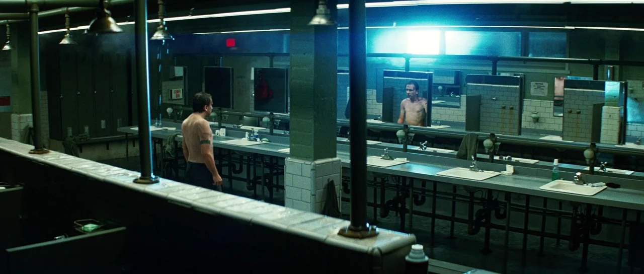 The Incredible Hulk (2008) movie still: wide — A spacious locker room features long rows of industrial sinks and tiled walls. A shirtless man stands…
