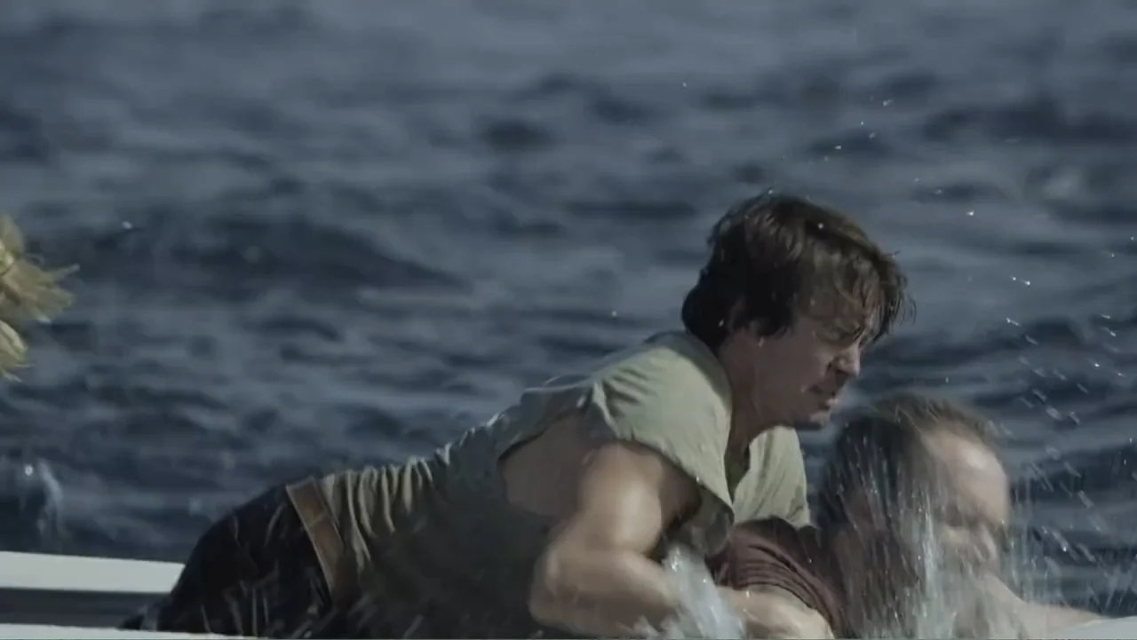 Capsized: Blood in the Water (2019) movie still: medium — Two men grapple on the deck of a boat surrounded by deep ocean water. One man attempts to…