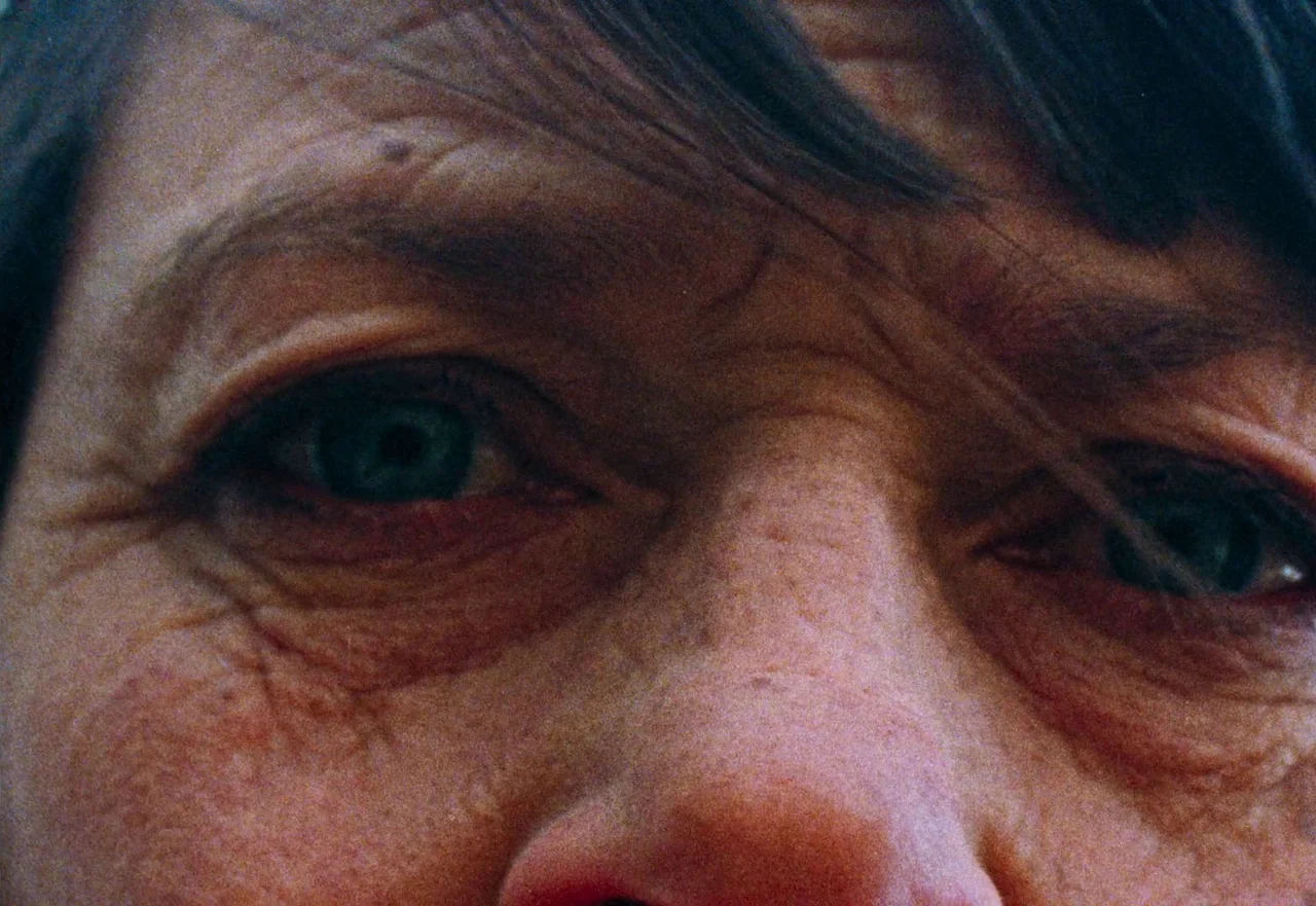 Enys Men (2022) movie still: closeup — A close-up view focuses on the eyes and brow of an elderly person. The skin shows deep wrinkles and a visible…