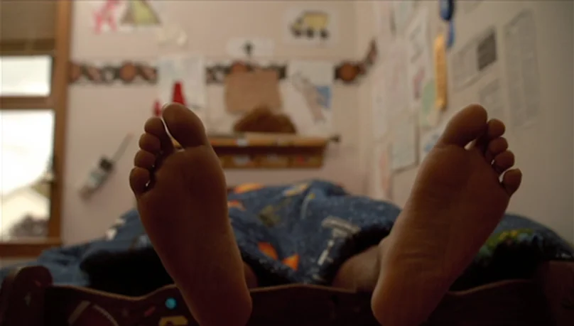 Mystery Team (2009) movie still: closeup — A child's bedroom wall is decorated with numerous hand-drawn pictures and posters. A pair of bare feet…