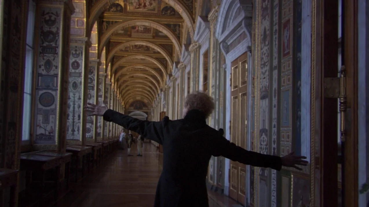 Russian Ark (2002) movie still: medium — An opulent, long vaulted hallway features ornate wall decorations and classic architectural arches. A…