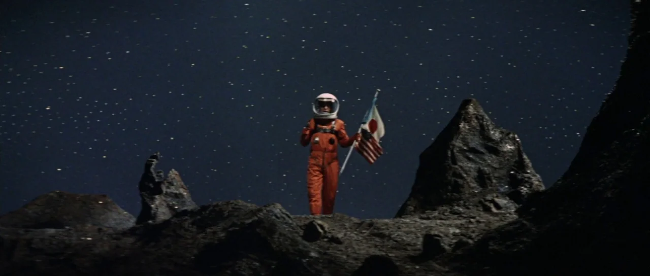 Invasion of Astro Monster (1965) movie still: fullbody — The barren, craggy lunar landscape is filled with sharp, dark volcanic rocks. An astronaut…