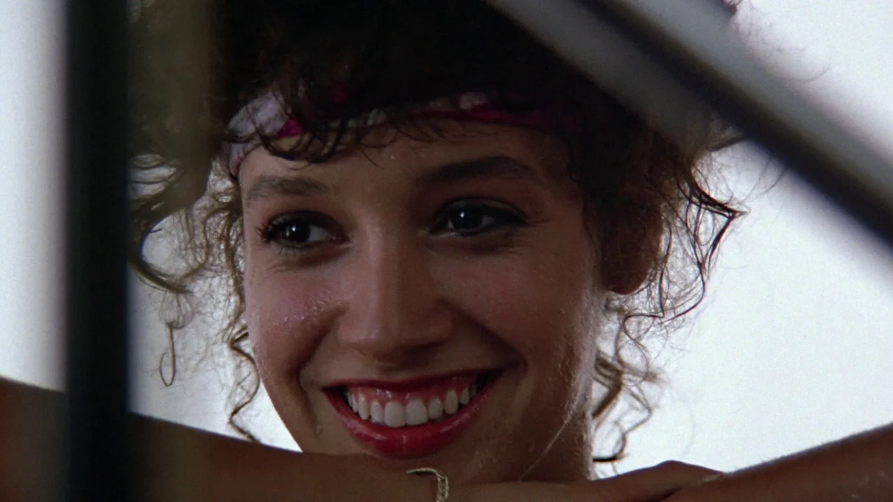 Flashdance (1983) movie still: closeup — The interior of a vehicle serves as the setting for this close-up shot. A young woman with curly hair…