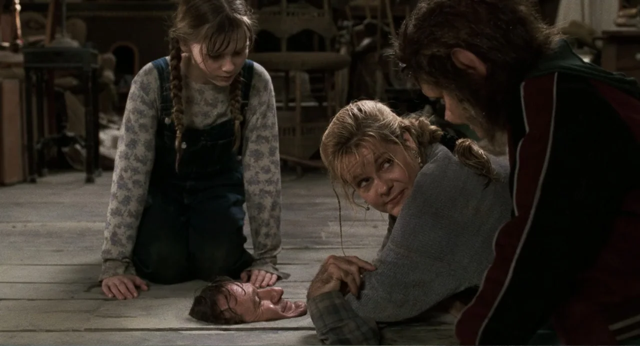 Jumanji (1995) movie still: medium — A dark, cluttered attic features worn wooden floorboards and stacks of stored furniture pieces. Three people…