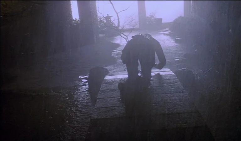 A Clockwork Orange (1971) movie still: wide — A dark stone bridge arches over a rainy expanse during a stormy night. A lone figure kneels on the…