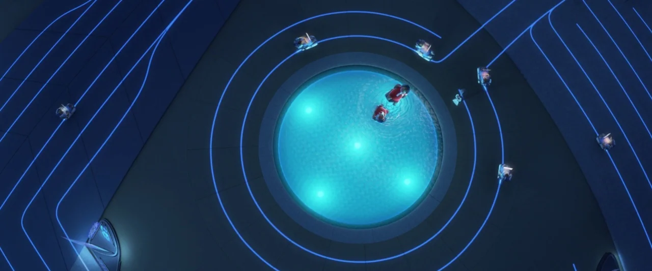 Wall-E (2008) movie still: establishing — A dark, modern plaza features a circular illuminated fountain surrounded by glowing geometric blue lines.…