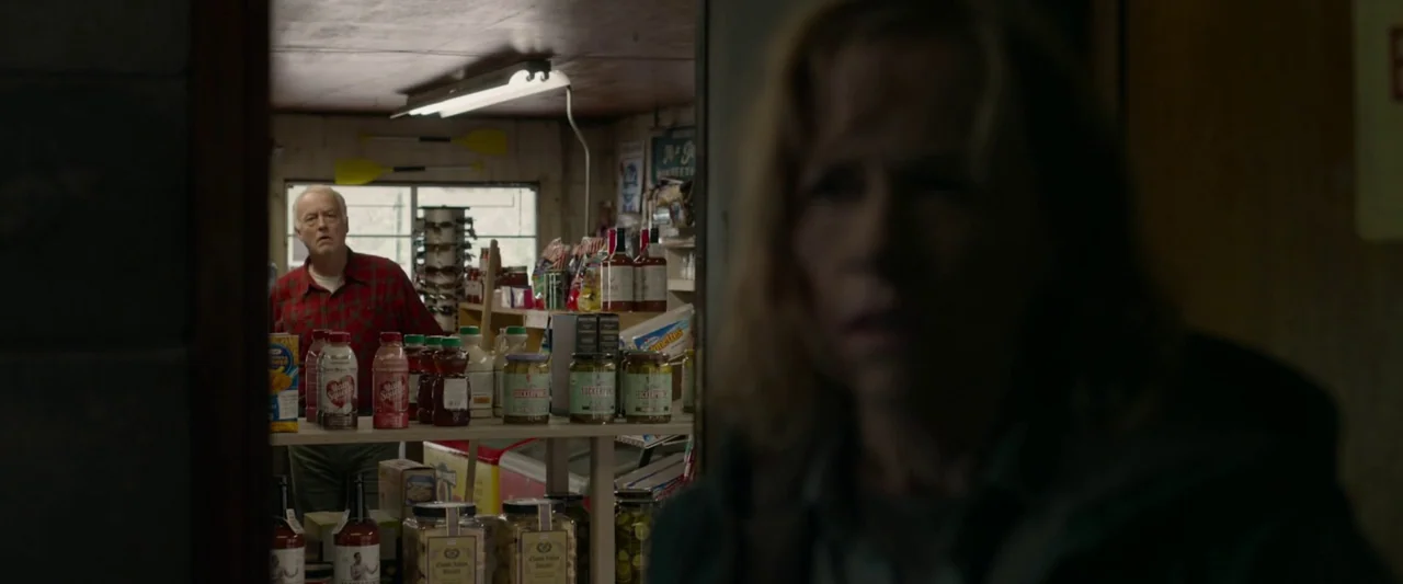 The Hunt (2020) movie still: medium — A small rural store with shelves stocked with various jars, bottles, and snack products. An elderly man stands…