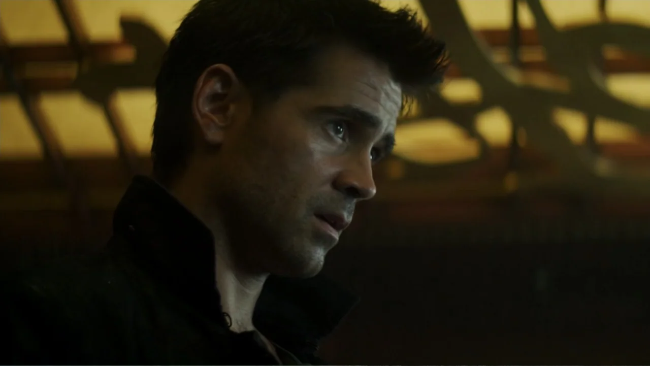 Total Recall (2012) movie still: closeup — A dimly lit indoor space features blurred, decorative golden wall patterns in the background. A man…
