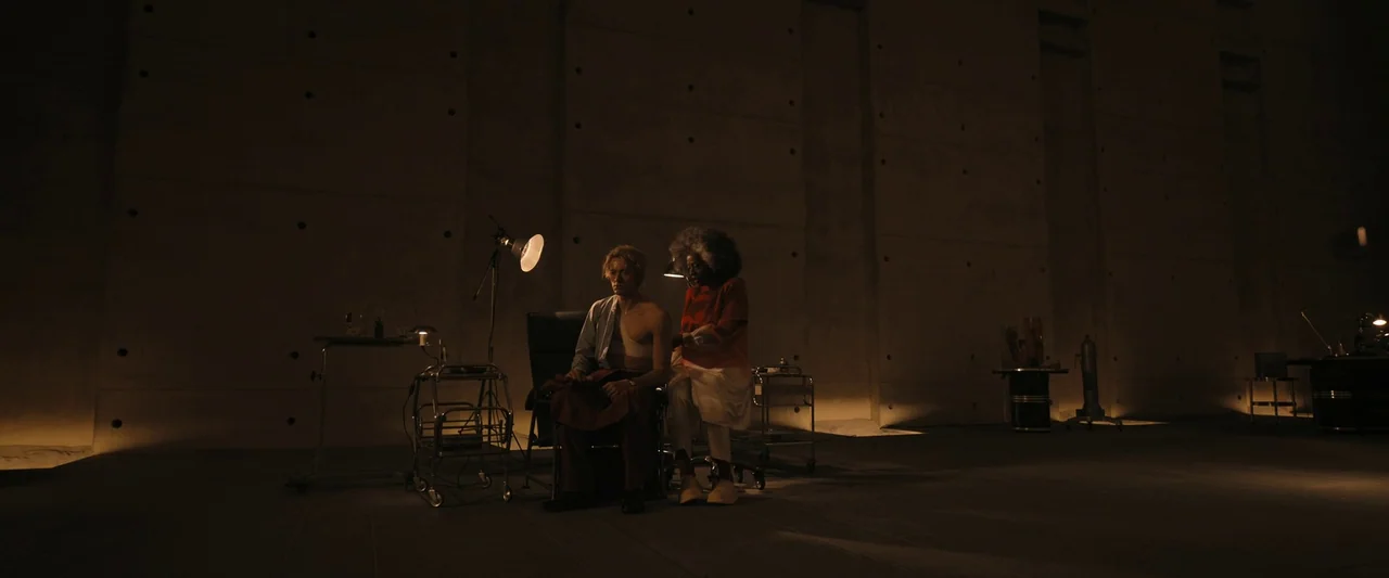 The Hunger Games: The Ballad of Songbirds & Snakes (2023) movie still: wide — A vast, minimalist concrete room features exposed wall ties and…
