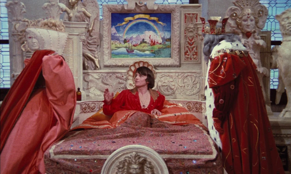 Donkey Skin (1970) movie still: medium — A lavish royal chamber features ornate white carved furniture and a framed rainbow landscape painting. A…