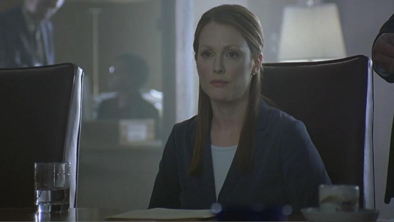 Hannibal (2001) movie still: medium — A dark, professional office space featuring leather chairs and a table with documents. A woman in a dark…