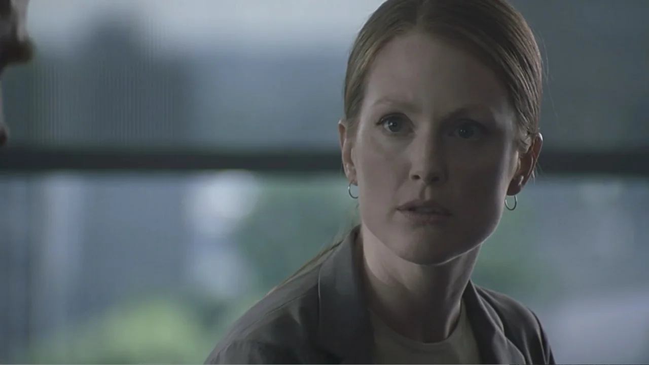 Hannibal (2001) movie still: closeup — A modern office interior featuring a large window with blurred daylight visible outside. A woman in a gray…