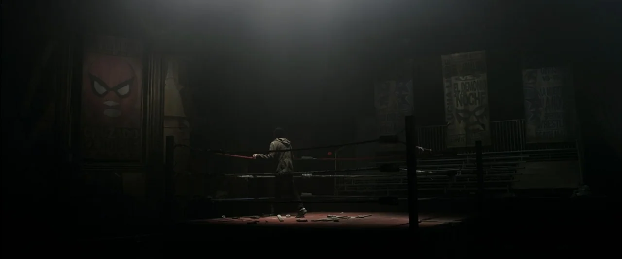 The Amazing Spider-Man (2012) movie still: wide — A dimly lit, abandoned boxing ring sits beneath a single bright overhead spotlight. A lone youth…
